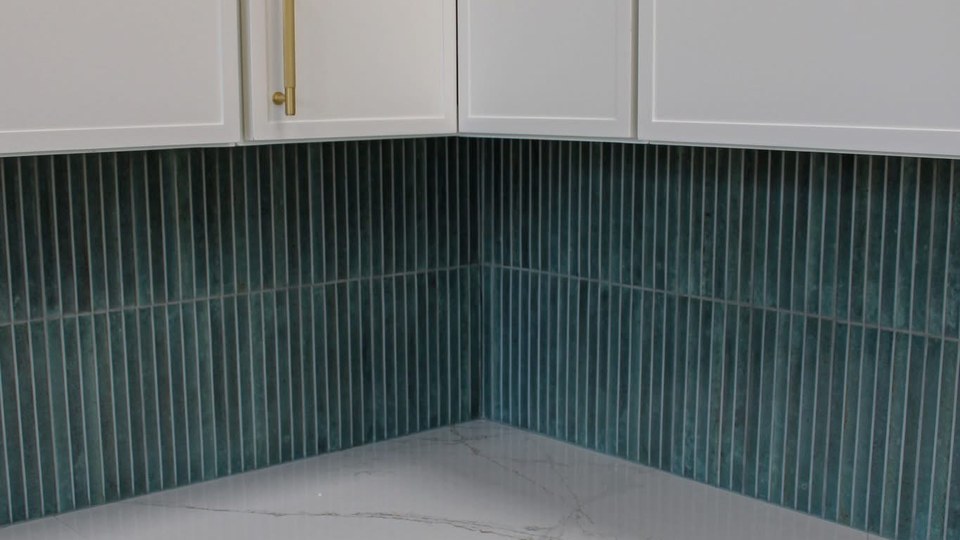 Emerald green fluted tile kitchen backsplash with brass cabinet pulls and white marble quartz countertops