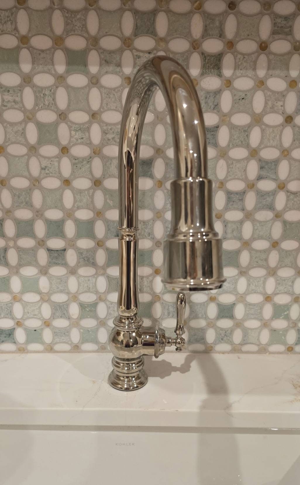 Freestanding soaking tub with deck-mounted brass faucet and marble backsplash wall