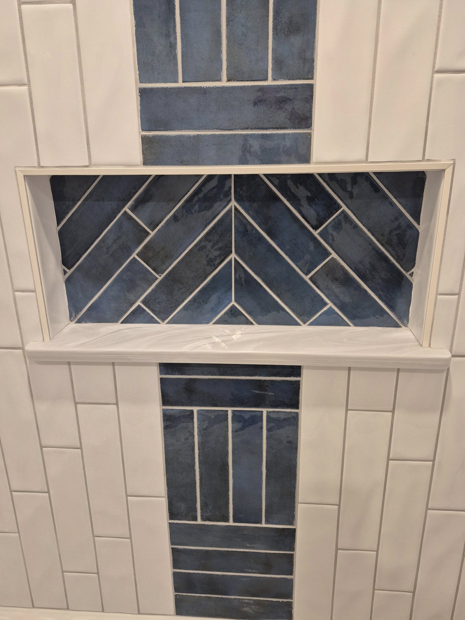 Herringbone marble tile surrounding a freestanding tub