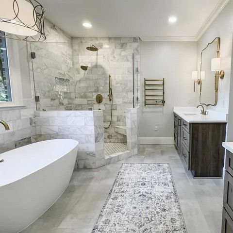 White marble master bathroom with freestanding tub, walk-in shower, and brass fixtures