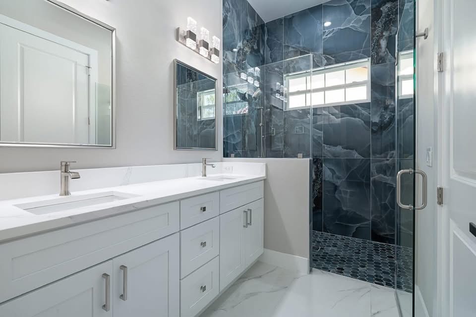Navy marble tile shower with glass doors and double vanity