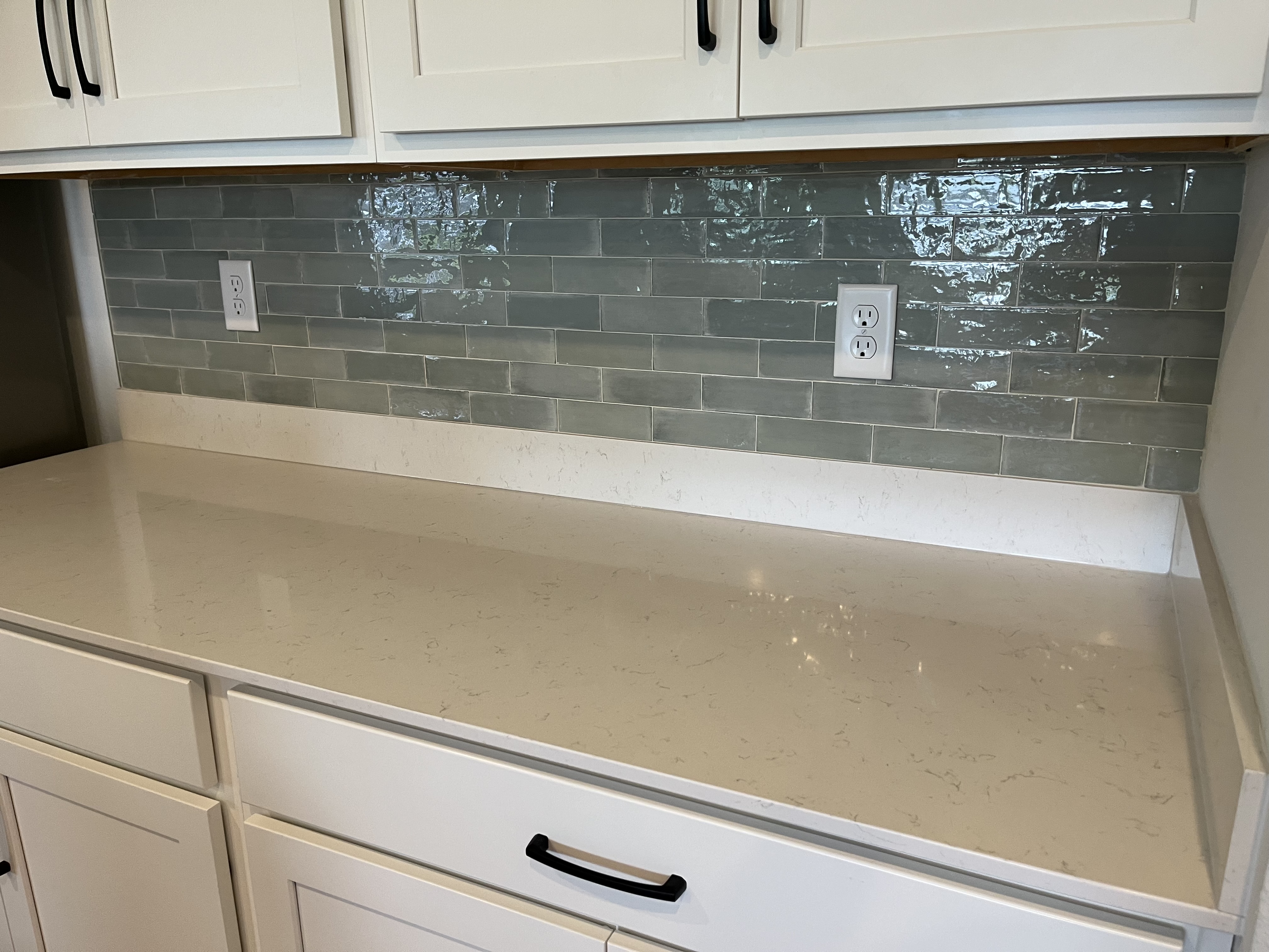 Sage green subway tile kitchen backsplash with white quartz countertops