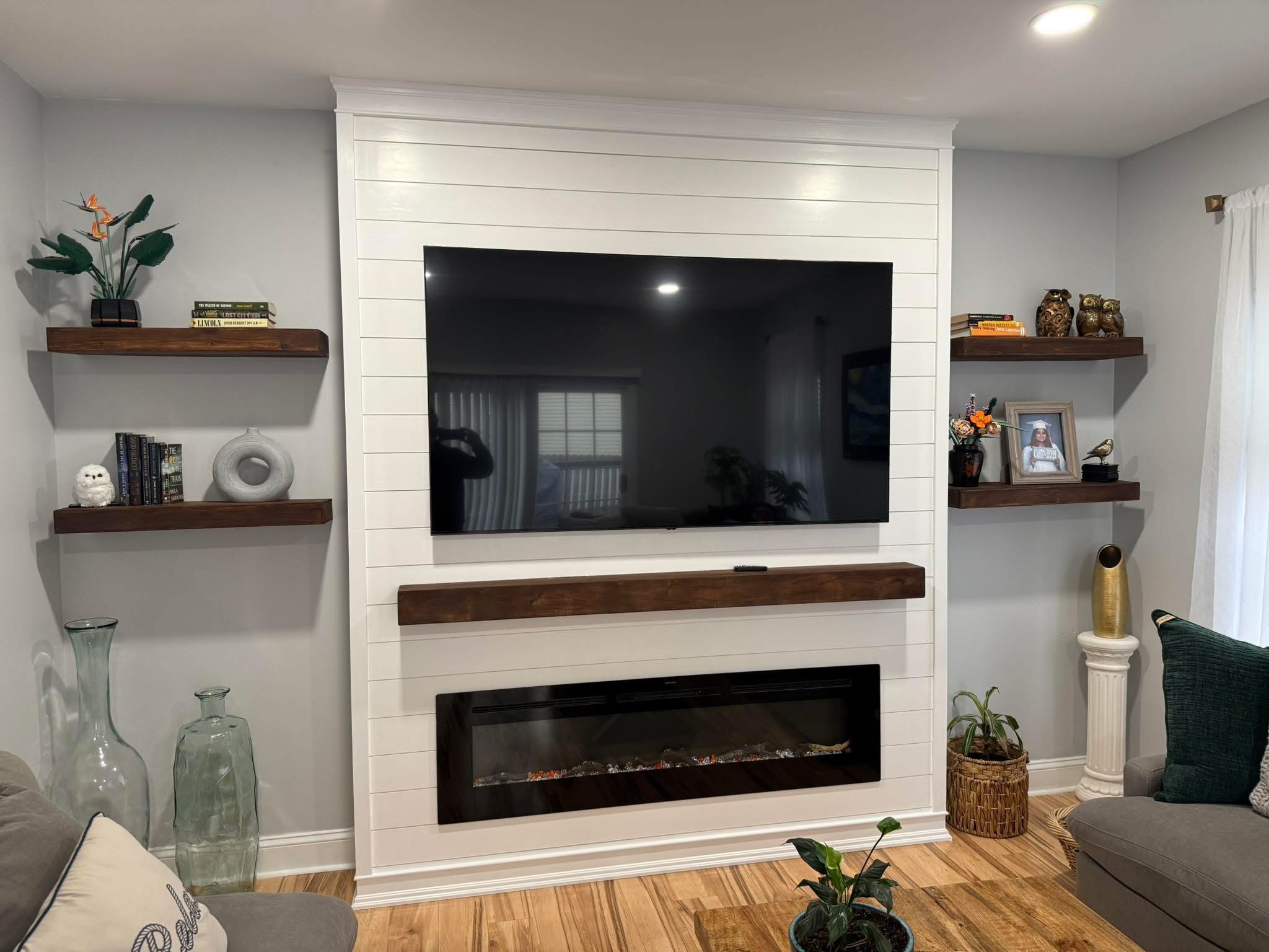 Custom white shiplap fireplace wall with mounted TV and floating walnut shelves built by Jeff Handyman
