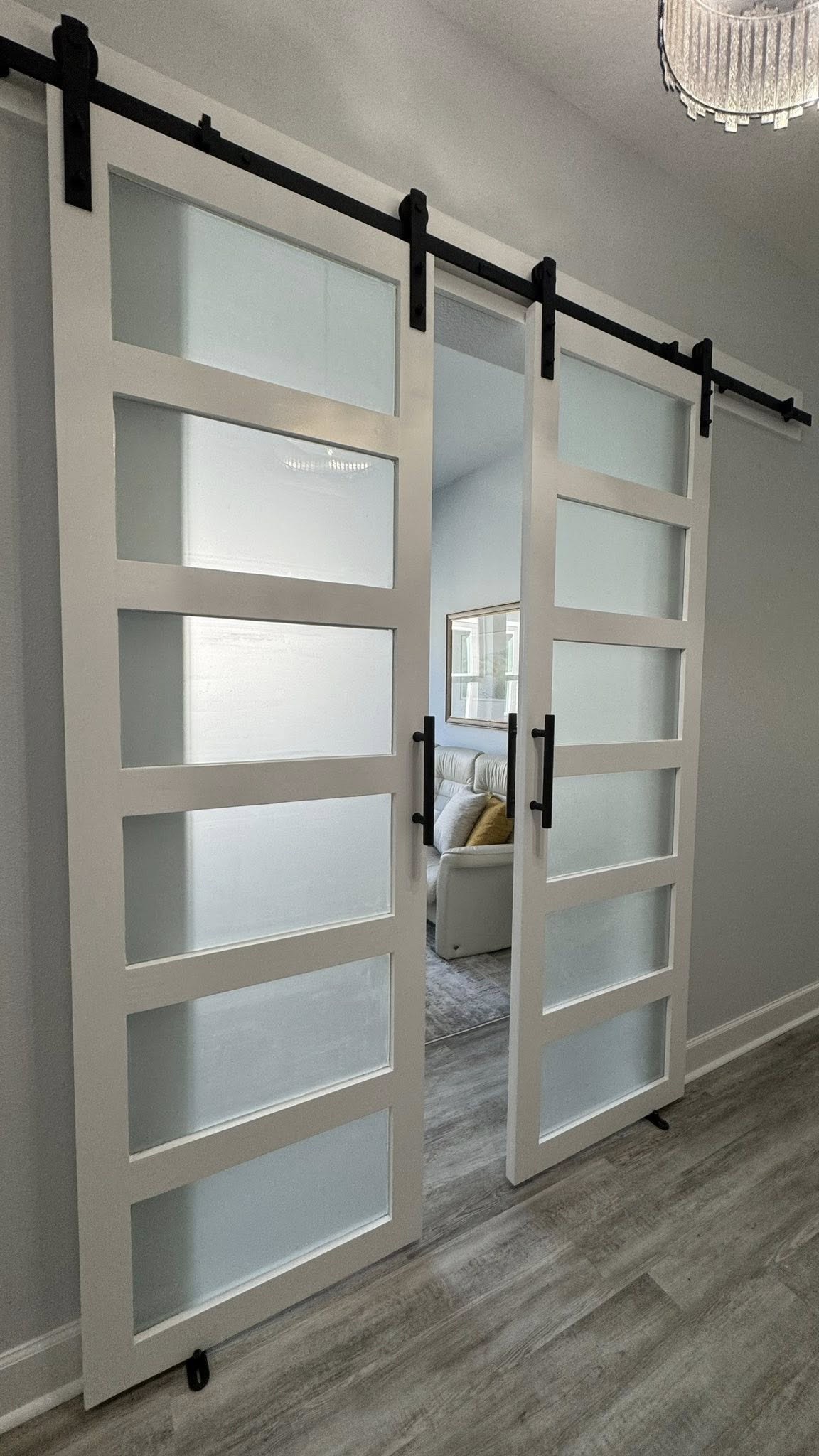 White sliding barn doors with glass panels and black track hardware