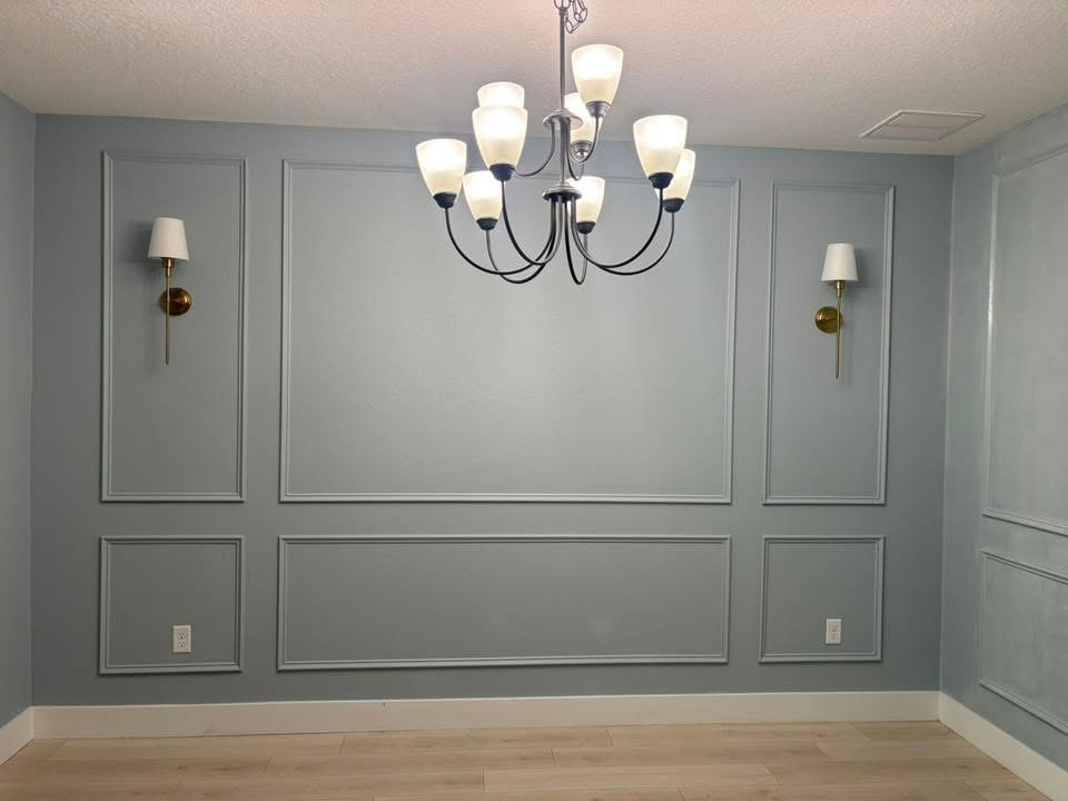 Wainscoted dining room painted sage blue with chandelier and wall sconces